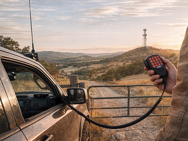 BTECH GMRS-50V2 mobile radio in use from a vehicle at sunset